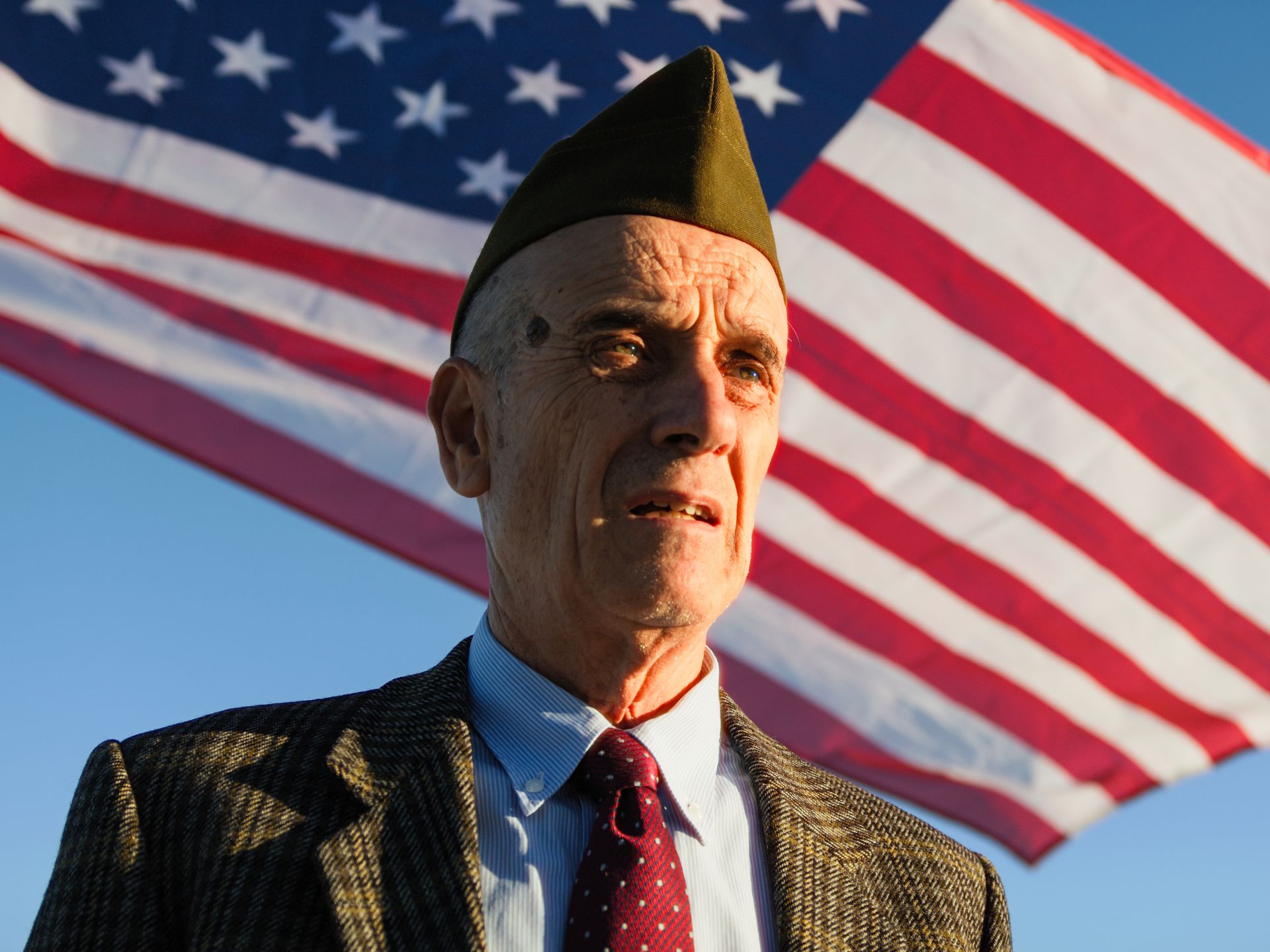 A senior veteran standing in front of the American flag.