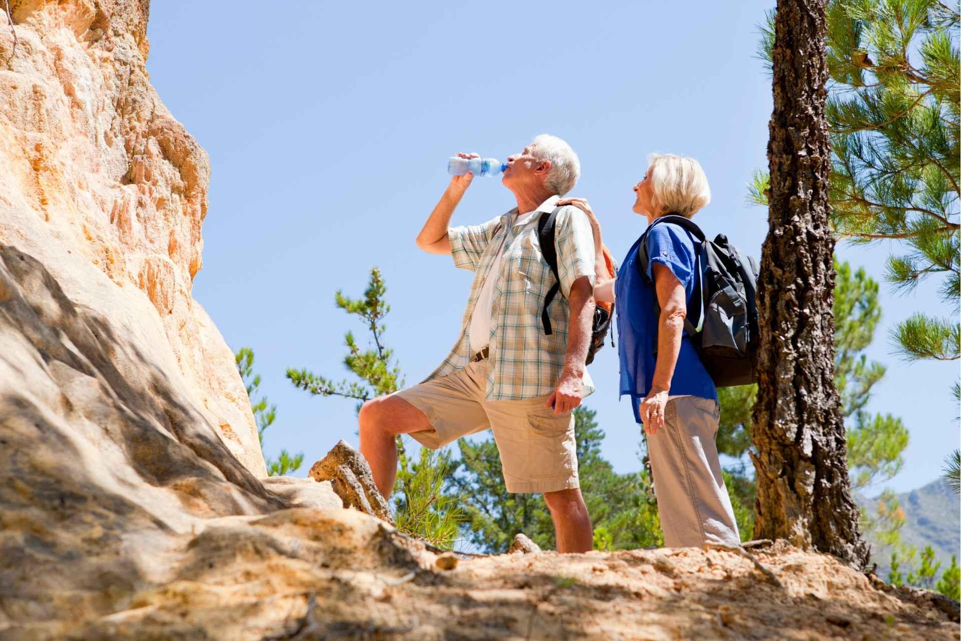 A senior couple on a hike and hydrating with water.